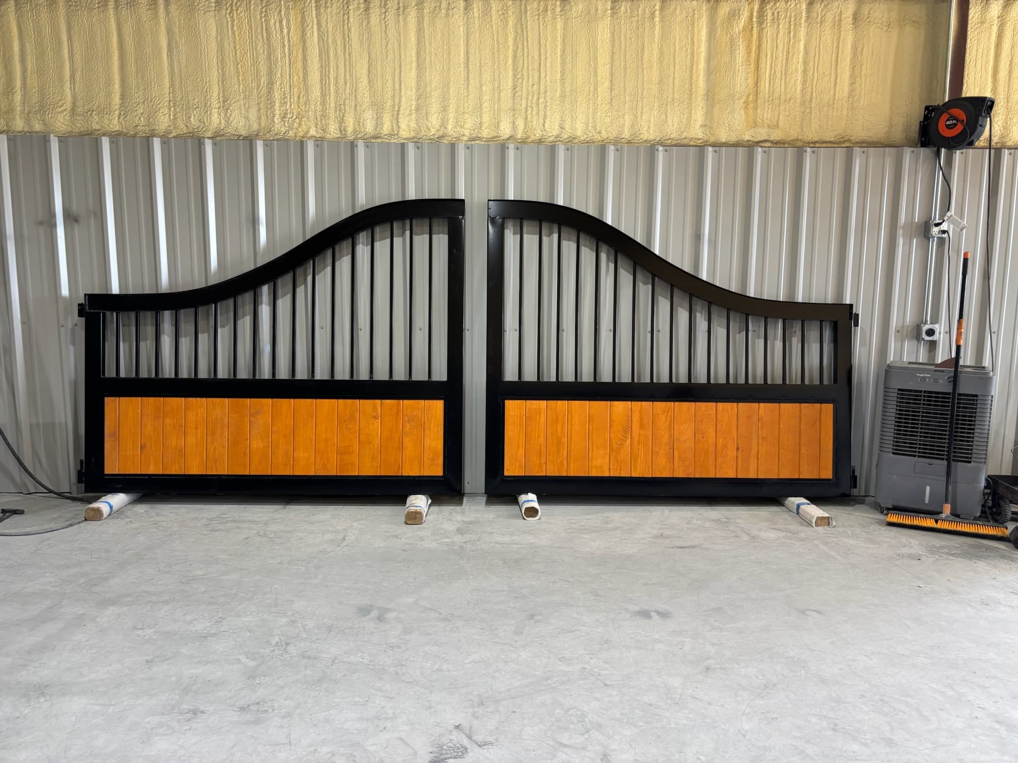 Finished custom steel gate with warm wood panel inserts in the shop