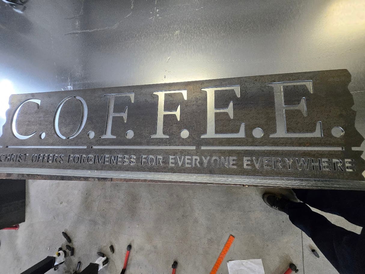 Plasma cut C.O.F.F.E.E. sign laid out on a shop floor